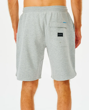 A person is seen from behind wearing Rip Curl Vaporcool Shorts with a black Adidas patch on the right pocket. The gray shorts, featuring an elastic waistband, fall to mid-thigh against a plain white background.