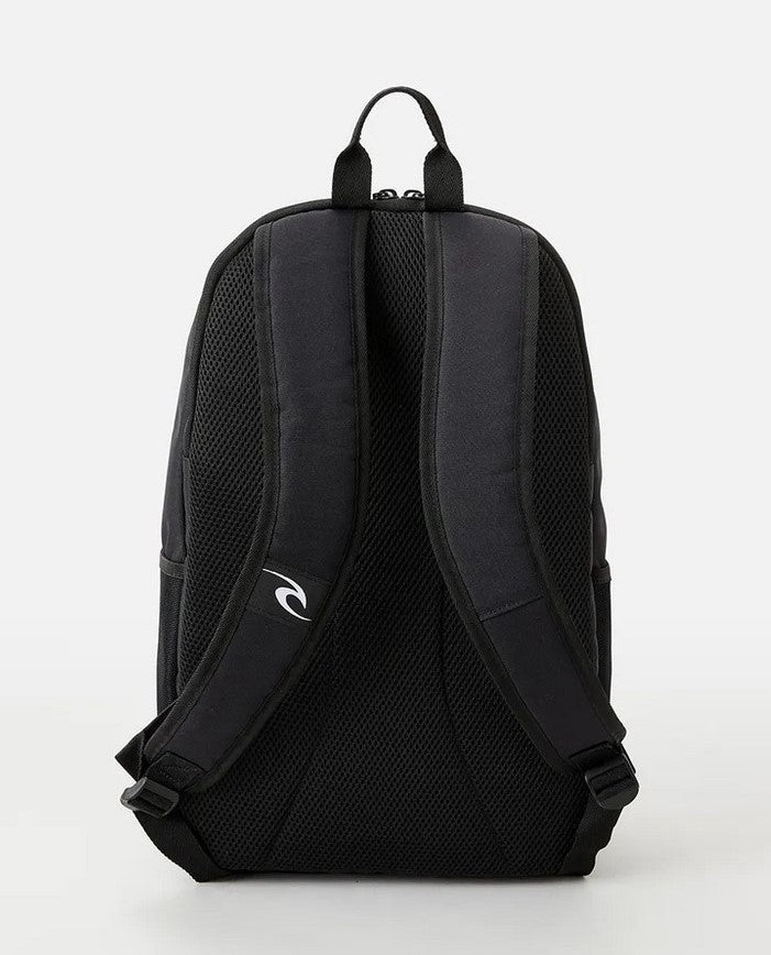 The Rip Curl Ozone 30L Icons Eco Backpack, crafted from recycled plastic, features a black design with padded shoulder straps and mesh back panel. A small logo embellishes one strap. It includes a secure laptop section for modern needs. The background is off-white.