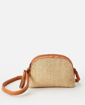 The Rip Curl Surf Gypsy Cross Body Bag is small and woven, featuring tan leather accents with a matching adjustable shoulder strap. This chic accessory has a zippered top and a detachable tassel keyring, set against a plain white background.