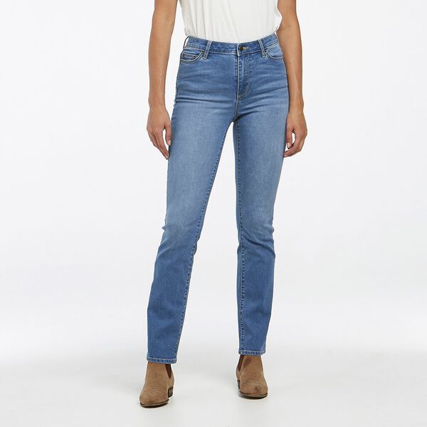 A person dressed in Rider Classic Mid Straight Jeans and a white shirt stands against a plain white background. The jeans’ mid-rise, straight-leg cut complements their look as brown ankle boots peek from beneath.