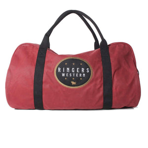 The Ringers Western Dusty Duffle Bag is a large, heavy-duty waxed canvas red duffel with black handles and straps. It features a circular black and gold logo on the front that reads "RINGERS WESTERN," with a star and bull design in the center.