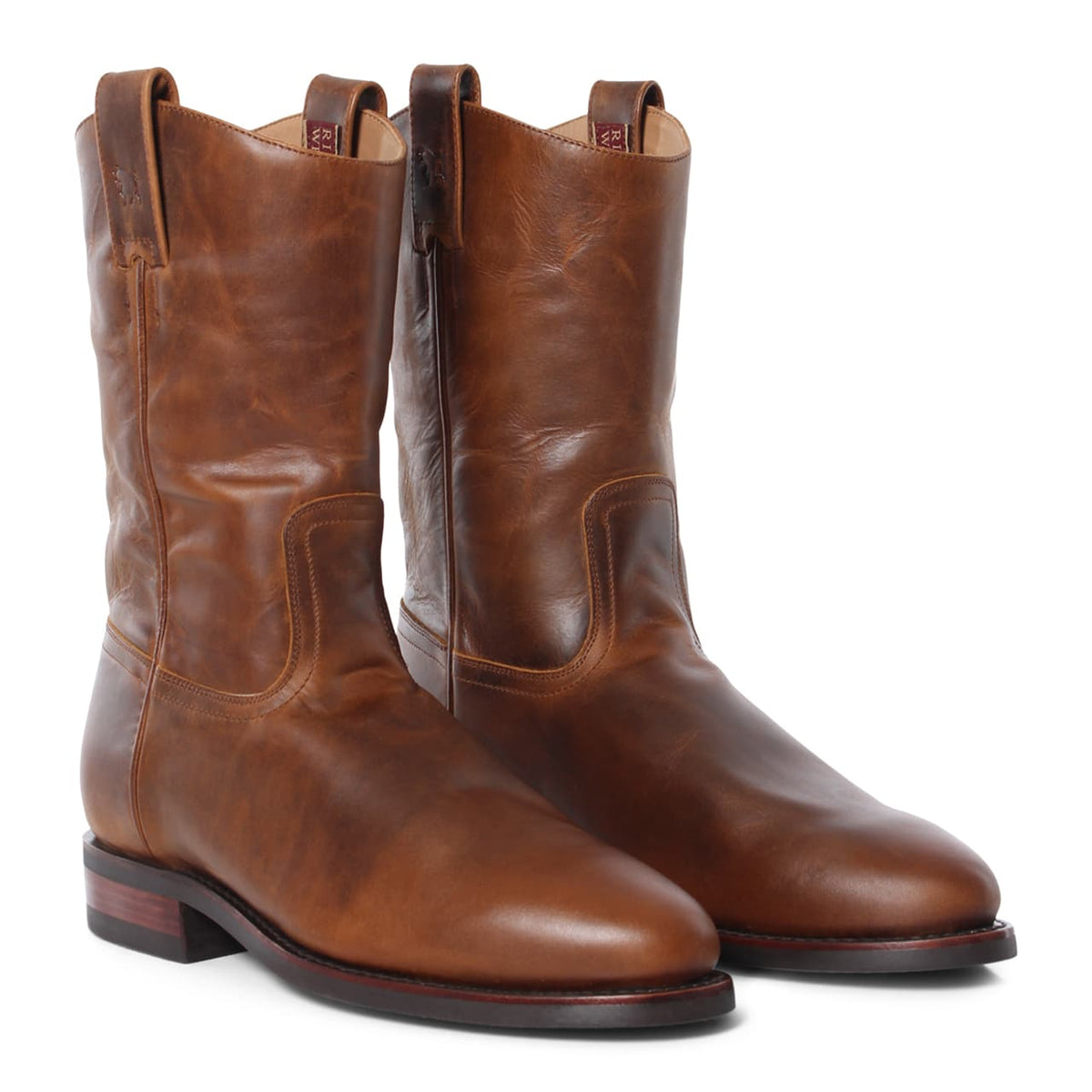 A pair of Ringers Western Kimberley High Boot cowboy boots made from genuine brown leather with a polished finish, featuring pull tabs at the top and a slightly pointed toe. These wide fitting boots have a low heel and visible stitching along the sides and upper part, positioned side by side.