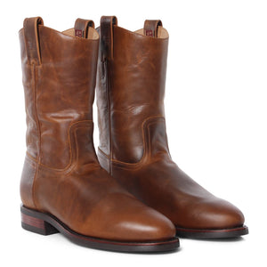 A pair of Ringers Western Kimberley High Boot cowboy boots made from genuine brown leather with a polished finish, featuring pull tabs at the top and a slightly pointed toe. These wide fitting boots have a low heel and visible stitching along the sides and upper part, positioned side by side.