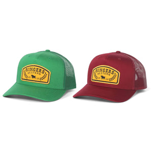 Two Ringers Western Wheatbelt Trucker caps—one green, one maroon—each with a yellow "Ringers Western" patch, mesh back, curved brim, and adjustable snapback closure for the perfect fit.