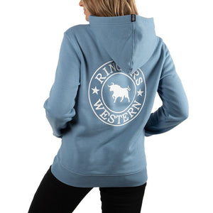 A person with blonde hair is wearing a light blue "Ringers Western Womens Signature Bull Hoodie" with the hood down. The back of this casual, comfortable hoodie features a circular logo with a white bull silhouette in the center and the words "RINGERS WESTERN" surrounding it. The person is standing casually with hands in pockets.