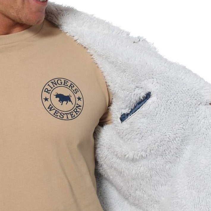 A person is partially visible, wearing a beige t-shirt with a "RINGERS WESTERN" logo featuring a bull and stars on the left chest. They are also sporting an open Ringers Western Duncan Denim Jacket with sherpa lining, perfectly showcasing the shirt underneath.