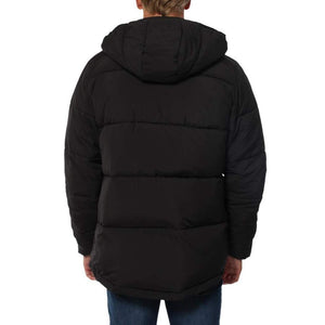 A person wearing a Ringers Western Bairnsdale Puffer Jacket with a detachable hood stands facing away from the camera. They are also wearing dark blue jeans.