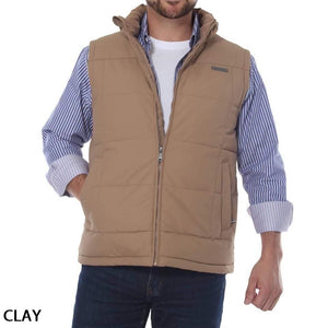 A man is wearing a Ringers Western Horsham Puffer Vest in tan, which has a soft fleece lining, over a white shirt with blue and white striped long sleeves. The vest, unzipped for a relaxed look, features an adjustable waist, and he has one hand in his pocket. The word "CLAY" is written in the bottom left corner.