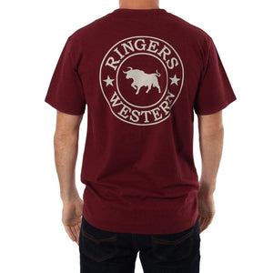 A person is wearing the Ringers Western Signature Bull Classic T-Shirt, a comfortable maroon crew neck featuring the "Ringers Western" logo on the back with a white bull silhouette flanked by stars. They're also sporting dark jeans against a plain white background.