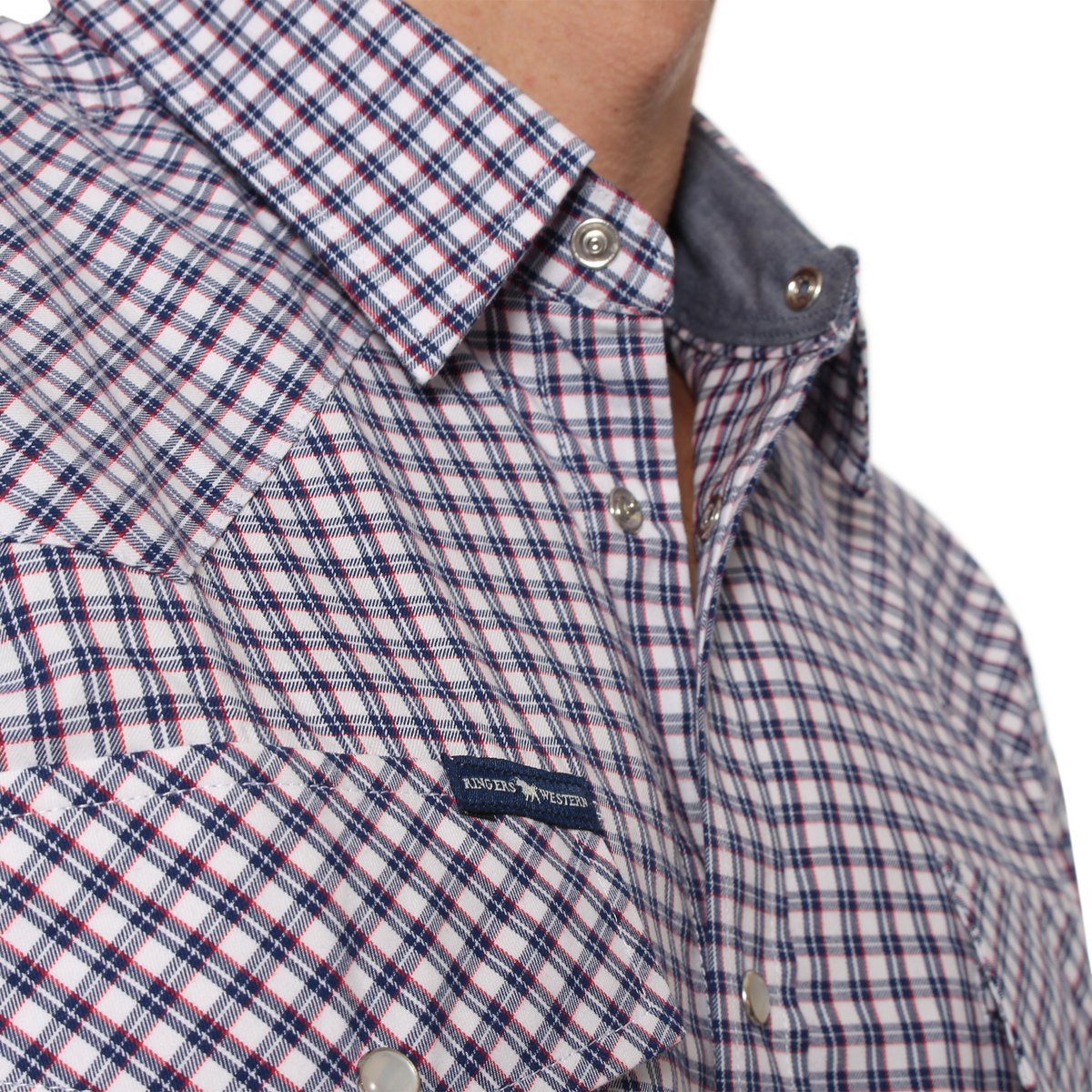 Close-up of a person wearing a Ringers Western Wyoming Shirt featuring a checkered plaid pattern with red, blue, and white lines. The shirt is detailed with metal snap buttons and a small, partially visible label. Made from 100% cotton, the collar includes a contrasting inner lining in a solid color. Only the lower part of the face is visible.