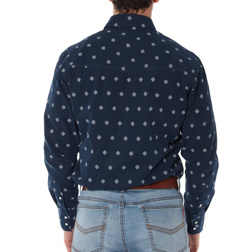 A person is standing with their back to the camera, wearing a dark navy blue Ringers Western Wyoming Shirt patterned with small white geometric shapes and light blue jeans with visible back pockets. The semi-fitted shirt, crafted from 100% cotton, has its sleeves buttoned at the wrists.
