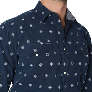 Close-up of a person wearing a dark blue, semi-fitted Ringers Western Wyoming Shirt with a white geometric diamond pattern. The 100% cotton shirt features a button-down front and two breast pockets. The person is pictured from the shoulders to the chest, set against a plain white background.