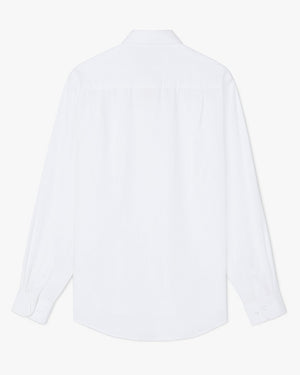 The RM Williams Collins Shirt is shown from the back in plain white, featuring long sleeves, a curved hem, buttoned cuffs, and a simple collar.