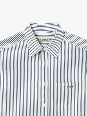 The RM Williams Collins Shirt, in white with thin black vertical stripes, is made from smooth twill cotton and includes a pointed collar, button front, front pocket, and visible brand label inside the collar.