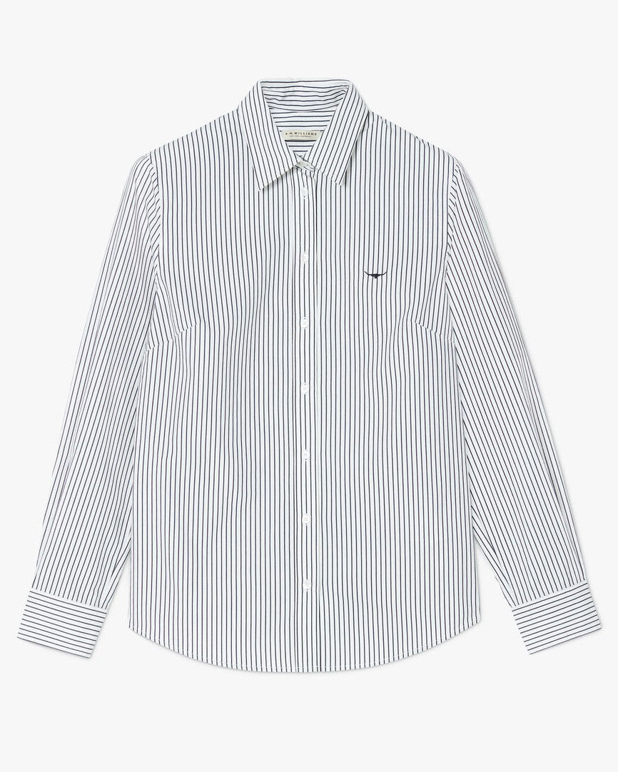 The RM Williams Nicole Shirt is a white, long-sleeved, 100% cotton button-up with vertical black pinstripes, a small black logo on the left chest, pointed collar, and buttoned cuffs.