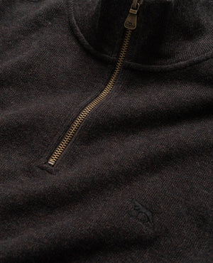 Close-up image of the Rodd & Gunn Alton Ave Sweat, a dark brown, 100% cotton zip-up sweater with a high collar. This relaxed fit piece features a small embroidered emblem of a dog near the bottom of the contrasting bronze zipper. The fabric appears soft and textured.