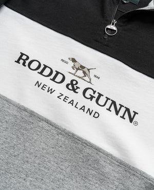This close-up of a Rodd & Gunn Hillop Sweat highlights its color block design in black, white, and gray. Made from 100% cotton, it features a logo with a pointing dog and the text "RODD & GUNN NEW ZEALAND.
