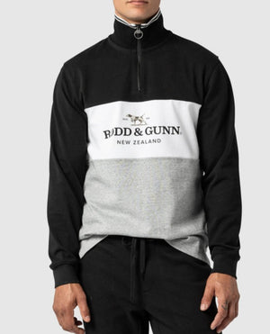A person is wearing a Rodd & Gunn Hillop Sweat jumper in black, white, and grey 100% cotton, featuring a "Rodd & Gunn New Zealand" logo on the front. The stylish half-zip sweatshirt has a high collar, and they are standing with hands in pockets against a plain background.