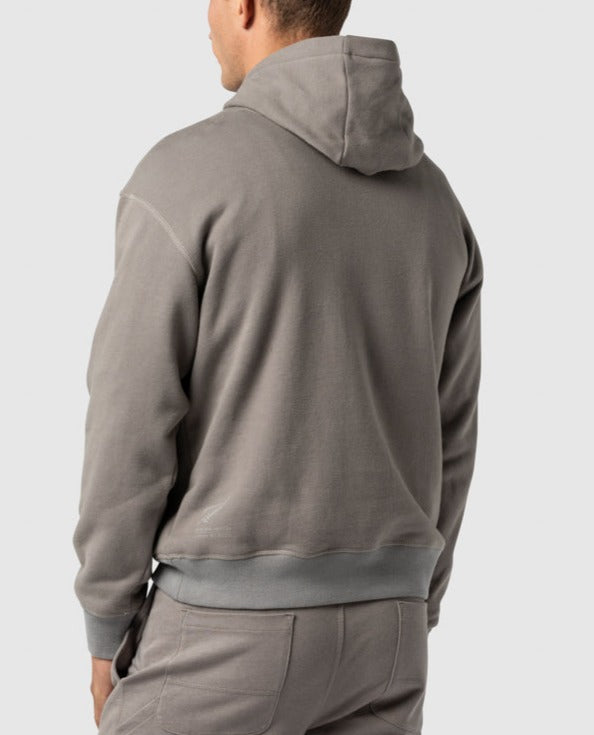 A person wearing the Rodd & Gunn Worser Bay Sweat hoodie and matching pants is seen from the back, featuring a Rodd & Gunn logo. The hoodie includes a hood and the fabric appears soft and comfortable. The image focuses on the upper half of the body, highlighting the back view and showcasing its soft fleece lining.