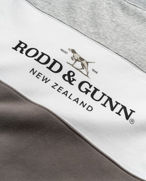 Close-up of a fabric panel from the Rodd & Gunn Mount Wesley Sweat, showcasing "Rodd & Gunn New Zealand" text and a dog logo. The fabric features light gray, white, and dark gray horizontal stripes with a cozy fleece lining for supreme comfort.