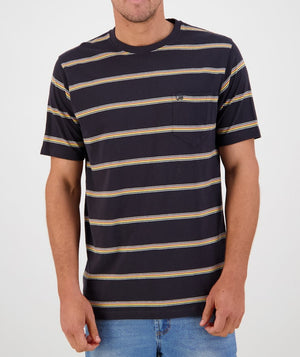 A person is standing in front of a plain light background, wearing the Swanndri Dome Valley Stripe Tee—a comfortable and casual, dark blue t-shirt made of 100% cotton. It features horizontal yellow and gray stripes along with a small square chest pocket on the left side adorned by the subtle Swanndri logo. The individual is also dressed in blue jeans.