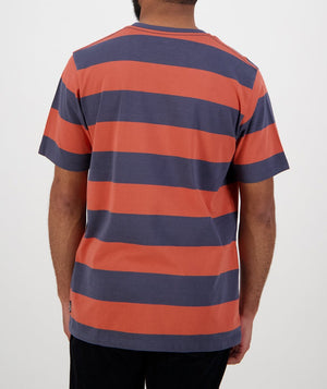 Seen from the back, a person wears the Swanndri Tomarata Stripe Tee, a casual 100% cotton shirt with wide horizontal orange and dark gray stripes and short sleeves, set against a plain white background.