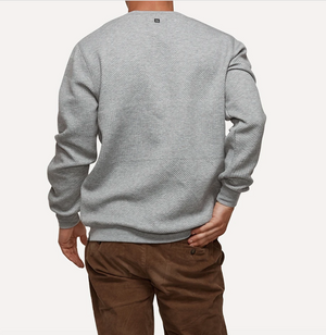 A person standing with their back to the camera, wearing the comfortable Industrie The Robinson Crew jumper in light gray and brown pants. The person has their left hand in their back pocket. The background is plain white.