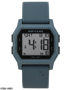 The Rip Curl Atom Digital Watch in steel grey is waterproof, shows the time as 4:18 and date Saturday 4/18, and has labeled mode, light, start, and reset buttons on a ribbed silicone strap.