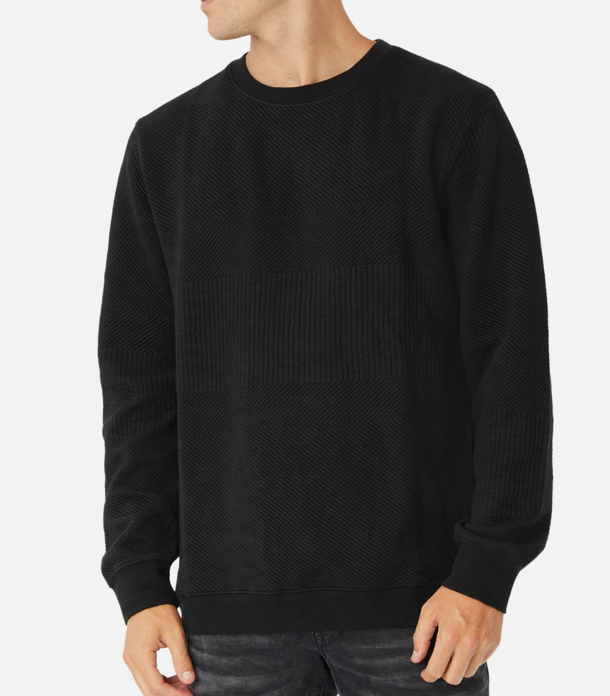 A person wearing the Industrie The Robinson Crew jumper, featuring subtle textured patterns, stands against a plain white background. The individual has their head turned slightly to the side, with one hand relaxed by their side and the other partially visible.