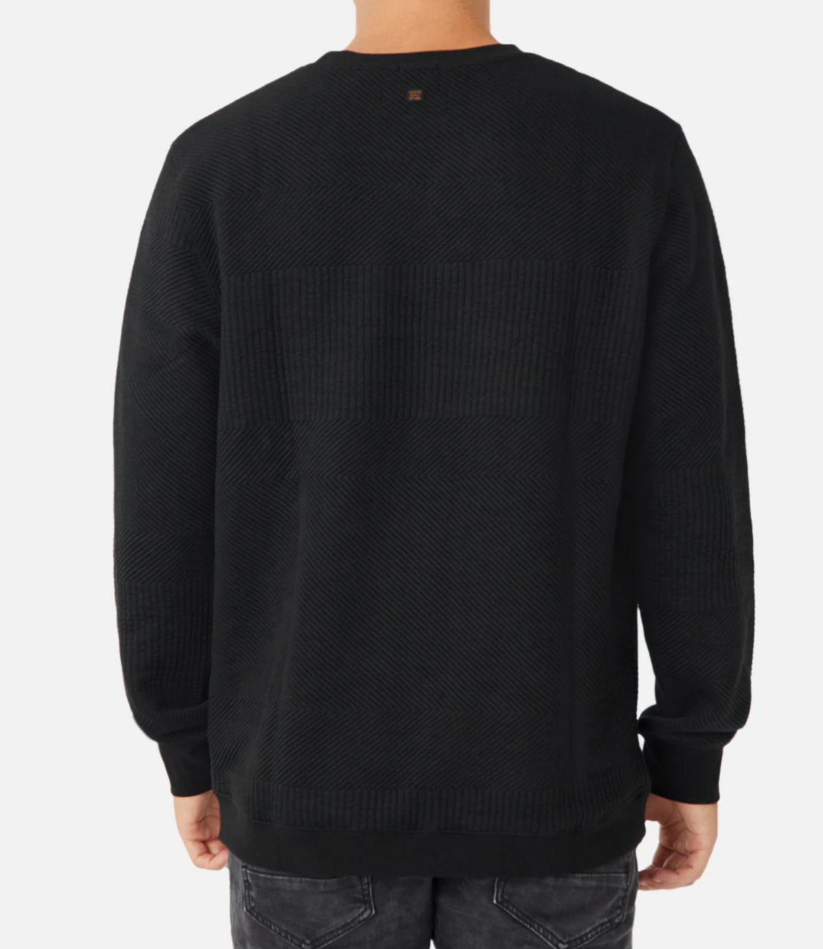 A person is seen from the back, wearing the Industrie The Robinson Crew, a black, long-sleeved, textured sweater paired with dark gray jeans. The comfortable jumper features a subtle pattern and a small brown tag at the top center of the back. The background is plain white.
