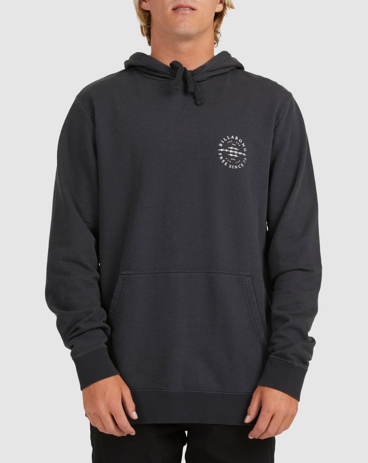 A person models the Billabong Big Wave Dan Hood, a black hoodie with a small white circular logo on the left chest, fleece lining, front pockets, and drawstrings, standing against a plain light background.