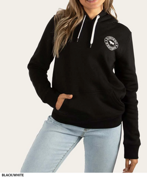 A person wearing a Ringers Western Women's Signature Bull Hoodie in black, featuring a white string and a circular logo on the chest, has one hand in the front pocket and is dressed in light blue jeans. The background is plain off-white.