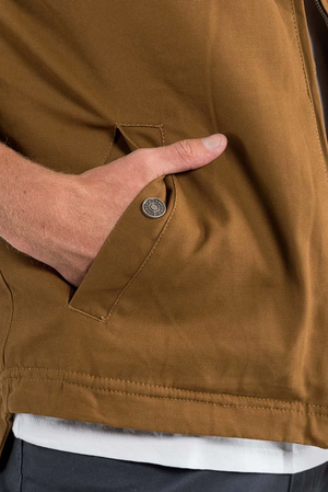 Someone wearing a brown Ringers Western Macquarie Canvas Vest with sherpa lining and button-detailed pocket flap. A white shirt is visible underneath, and the vest contrasts against a neutral background.