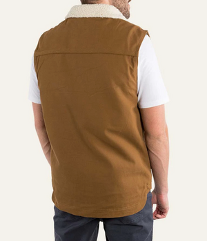 The person wears a Ringers Western Macquarie Canvas Vest in brown cotton with a shearling collar over a white T-shirt, viewed from the back. With dark pants, the look contrasts against the plain white background.