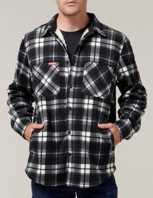 A person wearing the Hard Yakka Sherpa Bonded Fleece Jacket in black and white plaid, featuring sherpa lining and front pockets, stands with hands in the side pockets against a neutral background.