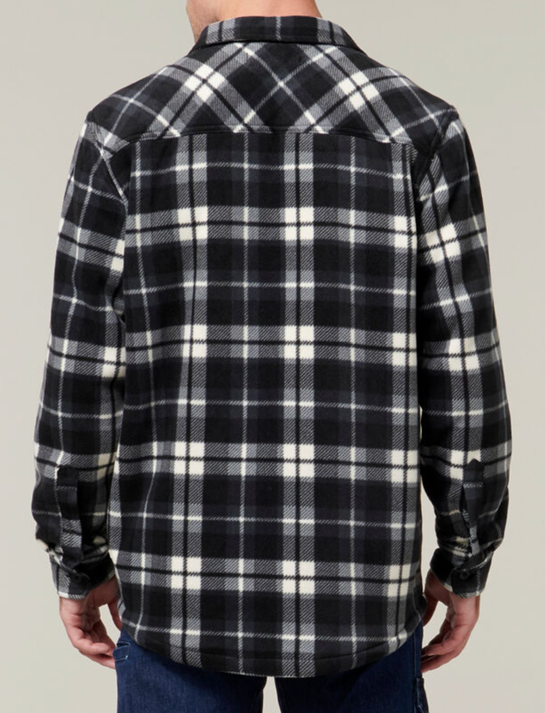 A person shown from the back wears the Hard Yakka Sherpa Bonded Fleece Jacket in black, white, and gray plaid with sherpa lining, pointed collar, and long sleeves—paired with blue jeans for a classic Hard Yakka style.