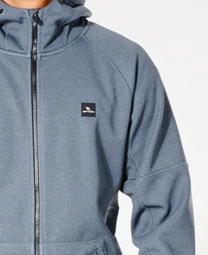 A person wears the Rip Curl Anti Series Storm Zip Thru, a gray hooded jacket with a chest logo and zipper. Ideal for winter, it features Durable Water Resistant fabric, a high collar, and tailored seams. Its sleek design stands out against a plain white background.