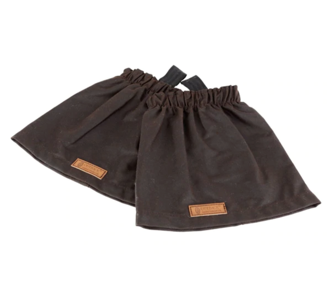 A pair of dark brown fabric Outback Oilskin Boot Guards, featuring elastic top and bottom edges. Each gaiter includes a small leather patch with embossed lettering. Designed for rugged adventures, these waterproof gaiters are displayed side by side on a white background.