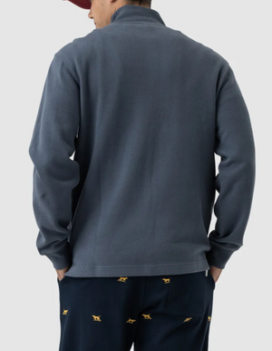 Rear view of a person wearing Rodd & Gunn Alton Ave Sweat, navy pants with a yellow animal pattern, and a red cap against a plain light gray background.