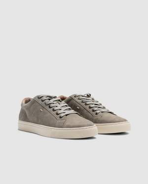 A pair of Rodd & Gunn Endeavour Spirit Sneakers in grey nubuck leather with white rubber soles and white lace-up closures. The shoes feature a minimalistic design with subtle stitching details and a small branded logo on the side. They are placed against a plain light background.