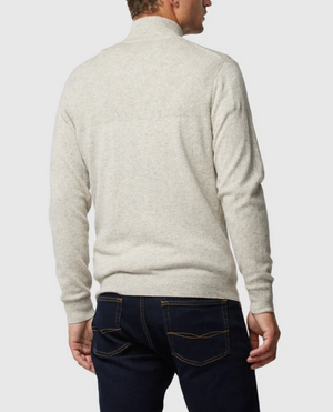 A person stands with their back to the camera, adorned in the Rodd & Gunn Little Mount Allan Knit, a light gray Australian Merino sweater featuring long sleeves and a ribbed texture. They pair it with dark blue jeans that showcase contrast stitching on the back pockets. The background is plain and light-colored.