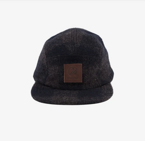 The Swanndri Wentworth Valley Cap is a dark wool cap featuring a structured bill and a leather patch with the Swanndri logo, showcasing a simple, classic design.