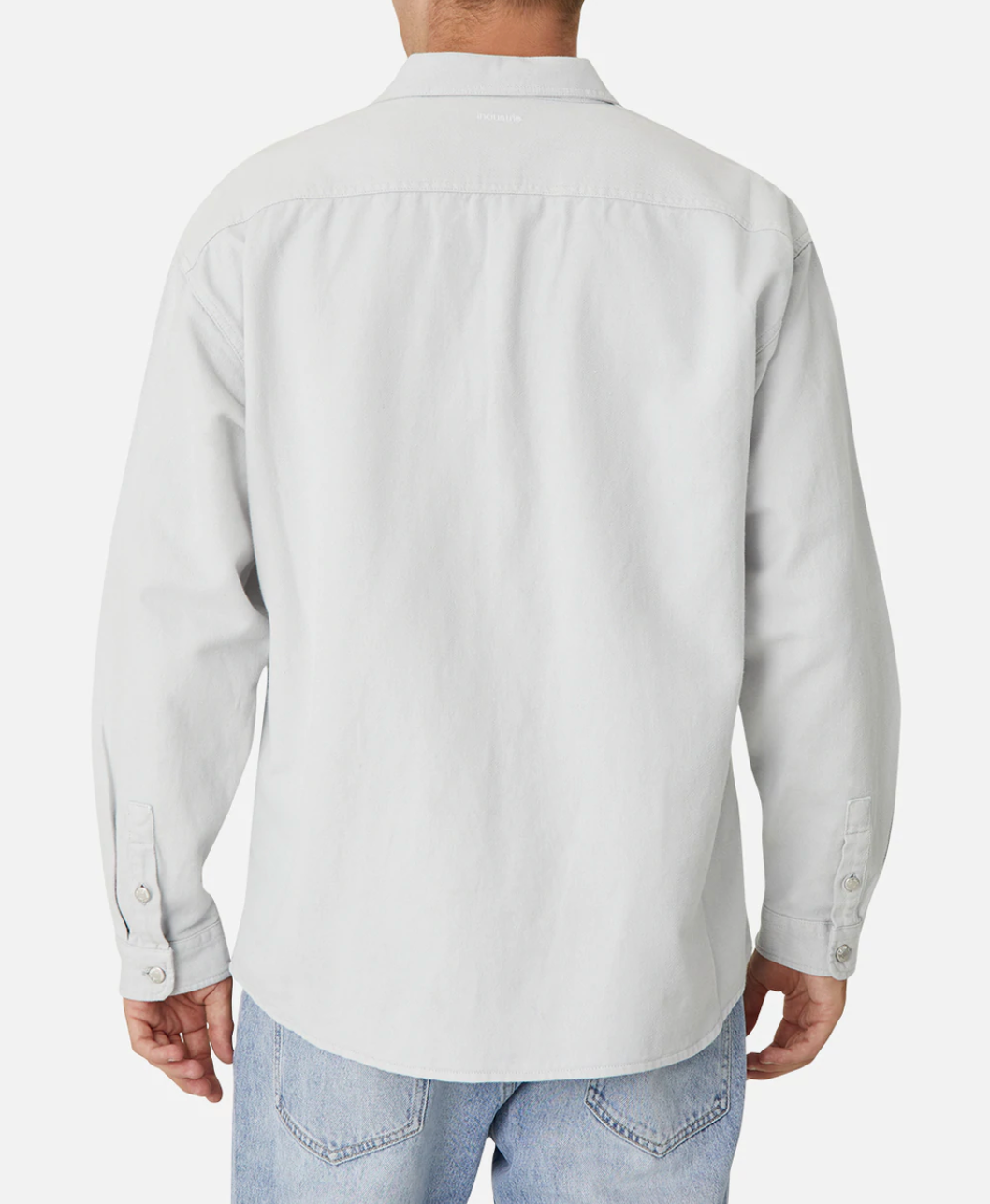 A person is standing with their back facing the camera, wearing a stylish Industrie The Portland Shirt in light gray, made from a Cotton/Linen blend, and light blue jeans. The shirt features a collar and buttons on the cuffs and subtly displays the Industrie logo. The background is white.