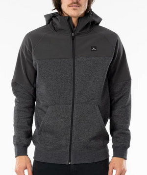 A person with long hair is wearing a Rip Curl Viral Anti Series Zip Thru Hood in dark grey, featuring a lighter grey midsection and kangaroo pockets. The durable water-resistant hoodie has a small black square logo on the left chest. The background is plain white.