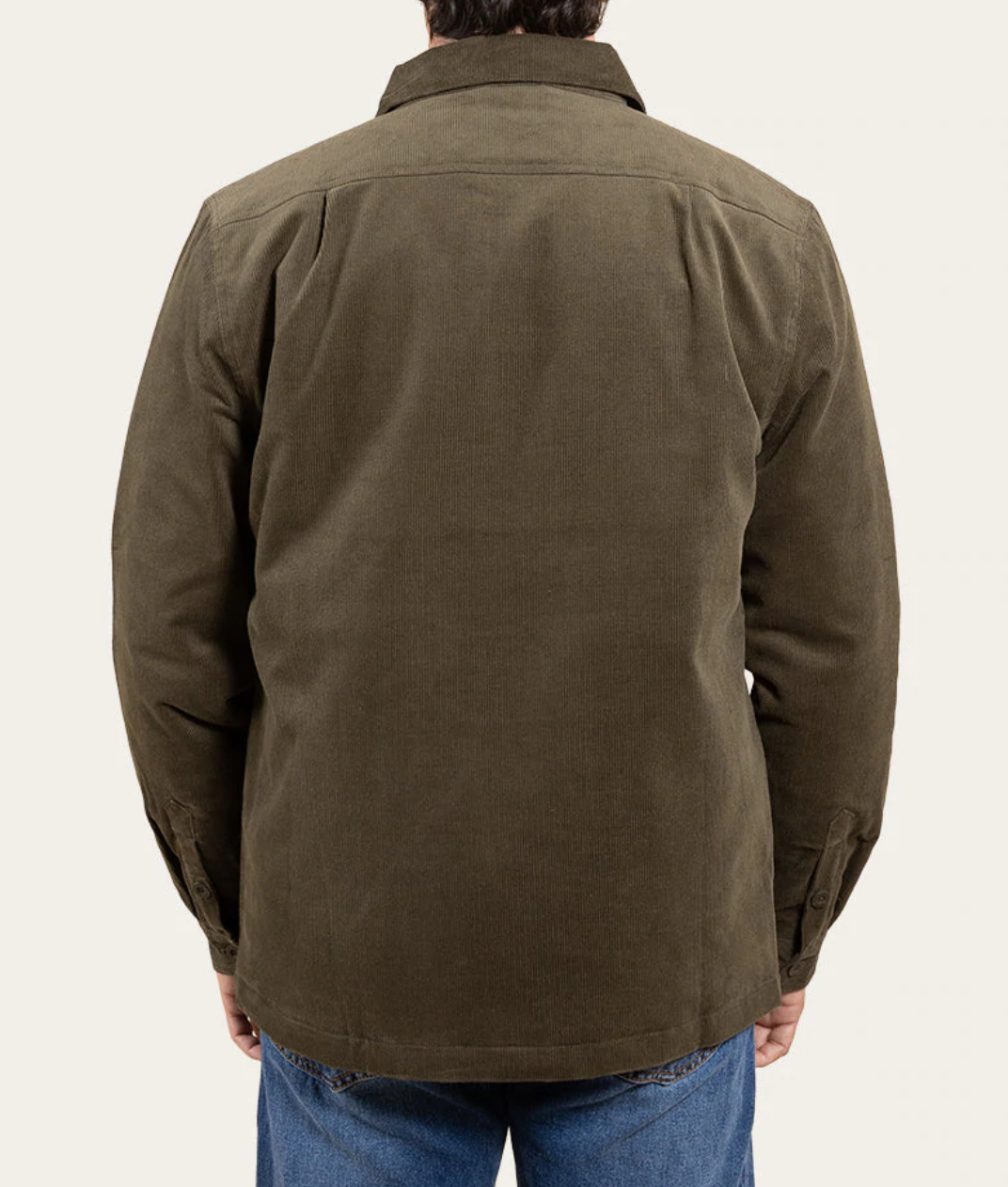 Wearing the Ringers Western Ashwell Overshirt, a sherpa-lined brown corduroy outer with a collar and long sleeves, a person stands with their back to the camera against a plain light-colored background, paired with blue jeans.