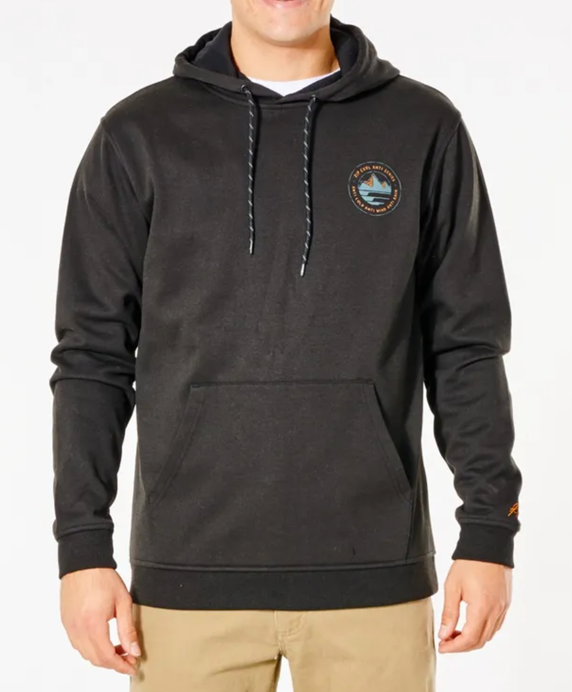 A person wears the black Rip Curl Anti Series Journey Hood, featuring a small circular left chest logo, front pocket, and Durable Water Resistant fabric, paired with beige pants, standing against a plain white background.