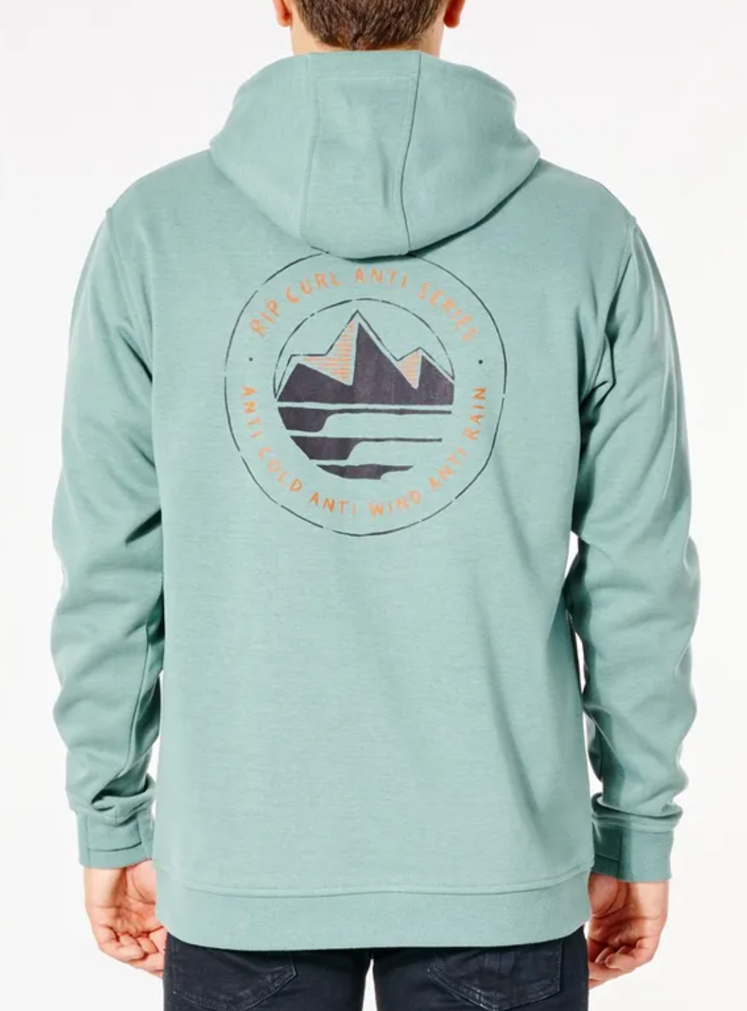 A person wears a Rip Curl Anti Series Journey Hood, a teal hoodie with a mountain graphic on the back, layered for winter. This durable, water-resistant design highlights protection against cold, wind, and rain.