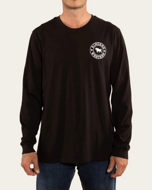 A person wearing the Ringers Western Signature Bull Loose Fit L/S T-Shirt, made of comfortable 100% cotton and featuring a circular "Ringers Western" logo on the left chest, pairs it with blue jeans against a plain, light-colored background.
