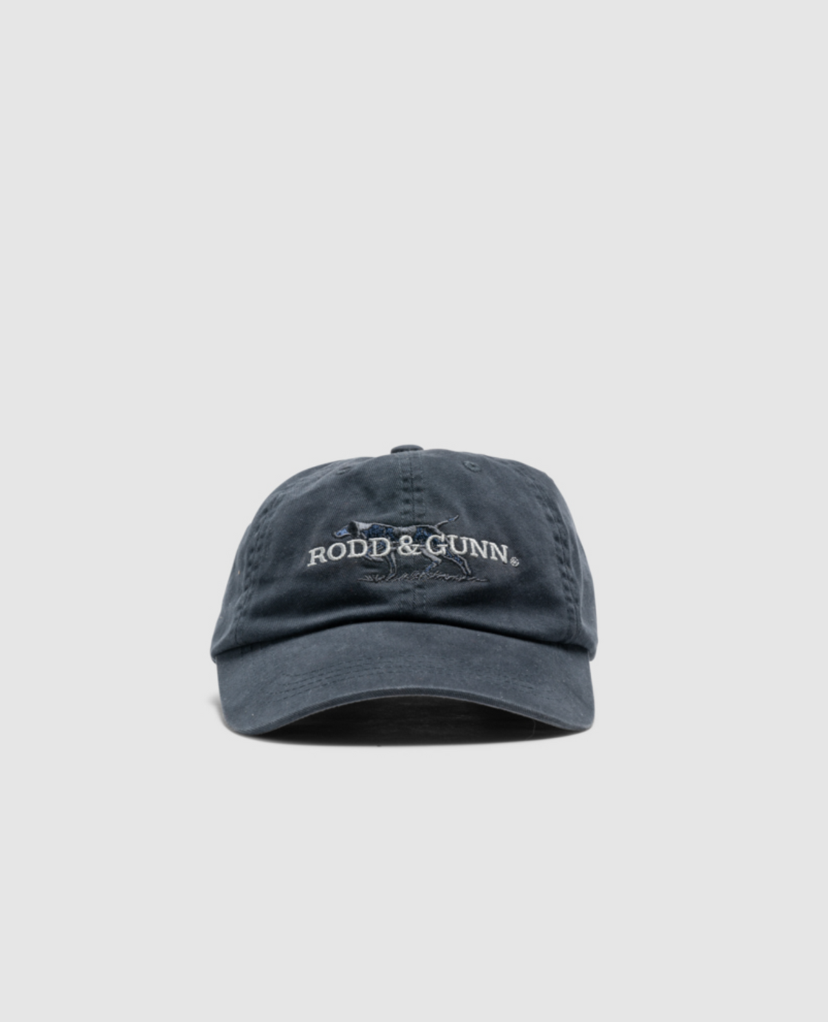 The dark blue Rodd & Gunn Double Barrel Cap features "Rodd & Gunn" embroidered in white on the front. Made from heavy-duty cotton twill with intentional slight wear, it blends style and durability against a plain gray backdrop.