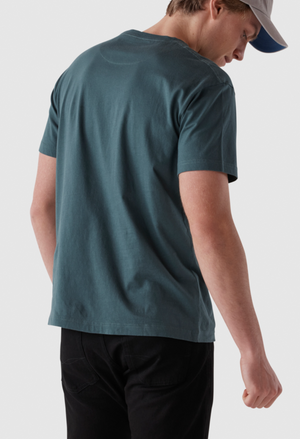 A person in a Rodd & Gunn The Gunn T-Shirt, made from Australian cotton in sports fit, paired with black pants and a light gray cap, is standing against a plain background. Captured from behind, the image emphasizes the comfort of the tee.